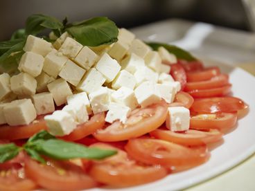 Nahaufnahme von Tomaten, Fetakäse und Basilikumblätter auf einem Teller