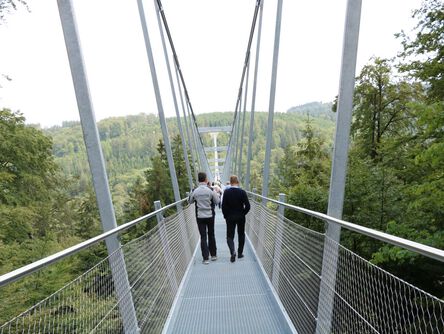 Personen laufen über die lange Hängebrücke 