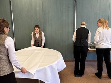 Azubis üben das Tisch eindecken in der Azubi-Akademie.