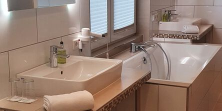 Badezimmer mit Badewanner zweischen zwei Waschbecken 
