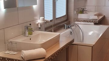 Badezimmer mit Badewanner zweischen zwei Waschbecken 