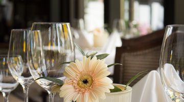 Weingläser und Blumen auf einem gedeckten Tisch 