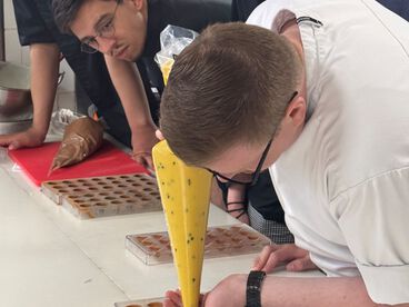 Azubis üben die Pralinenherstellung in der Azubi-Akademie.