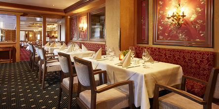  Restaurant mit zahlreichen gedeckten Tischen an rot gemusterten Sitzbänken 