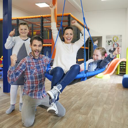 Eine junge Familie mit Kindern posiert glücklich im Indoor-Spielhaus "Sharkie-Island"