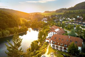 Luftaufnahme eines Hotels am See, umgeben von Natur.