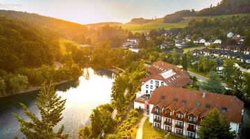 Luftaufnahme eines Hotels am See, umgeben von Natur.