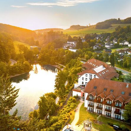 Luftaufnahme eines Hotels am See, umgeben von Natur.