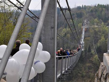 Menschen laufen in 100 Meter Höhe über eine Hängebrücke 