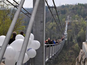 Menschen laufen in 100 Meter Höhe über eine Hängebrücke 