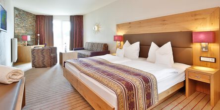 Helles Zimmer mit rot gestreiften Teppichboden und einem Doppelbett mit Naturholzrahmen