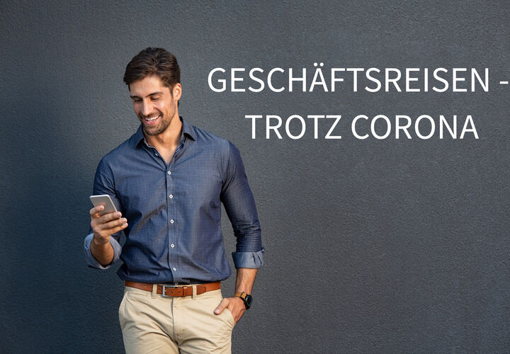 Mann steht vor einer garuen Wand und hält sein Smartphone in der Hand