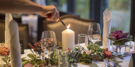  Kerze auf dem mit Blumen dekoriertem Tisch wird angezündet