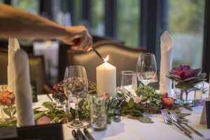  Kerze auf dem mit Blumen dekoriertem Tisch wird angezündet