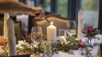  Kerze auf dem mit Blumen dekoriertem Tisch wird angezündet