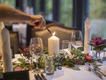  Kerze auf dem mit Blumen dekoriertem Tisch wird angezündet