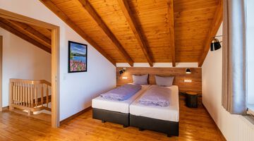 Gemütliches Schlafzimmer mit Holzbalkendecke und Doppelbett