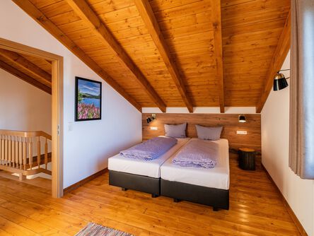 Gemütliches Schlafzimmer mit Holzbalkendecke und Doppelbett
