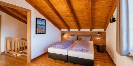 Gemütliches Schlafzimmer mit Holzbalkendecke und Doppelbett