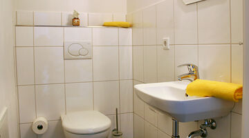 Toilette mit gelben Handtüchern am Waschbeckenrand