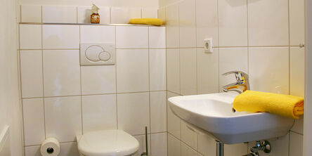 Toilette mit gelben Handtüchern am Waschbeckenrand