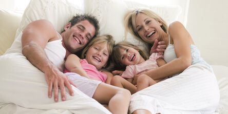 Eine junge Familie liegt im zusammen im Bett.