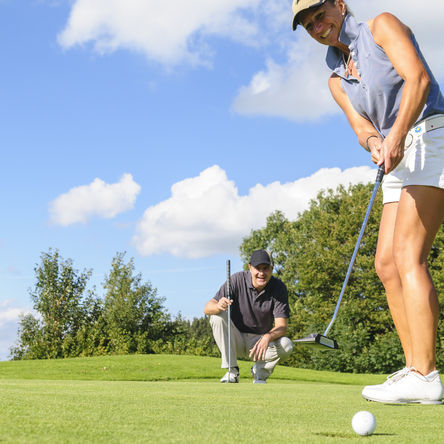Ein Pärchen spielt an einem soonigen Tag Golf auf einem Golfplatz