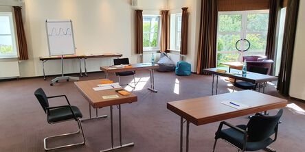 Besprechungsraum mit vorbereiteten Tischen und Blick in die Natur 