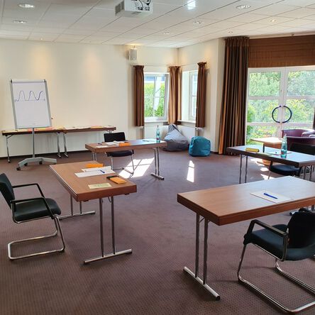 Besprechungsraum mit vorbereiteten Tischen und Blick in die Natur 