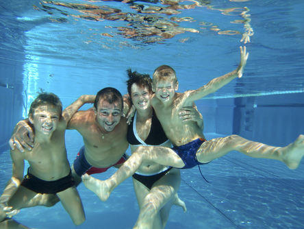 Familie im Schwimmbad unter Wasser 