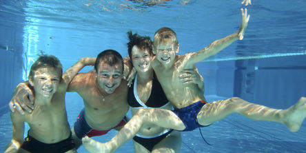Familie im Schwimmbad unter Wasser 