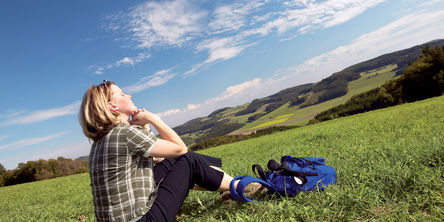 Eine Frau sitzt auf einer Wiese und genießt die Sonne und die Aussicht.