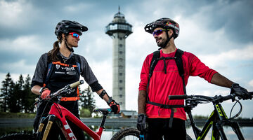 Paar mit Mountainbikes vor dem Ettelsbergturm schauen sich an 