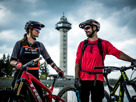 Paar mit Mountainbikes vor dem Ettelsbergturm schauen sich an 