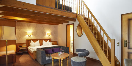 Familien-Maisonettezimmer mit einem Doppelbett und einer Holztreppe