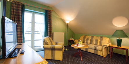 Wohnzimmer mit grüner Wandfarbe im Park Resort mit gestreifter Couch mit passendem Sessel 