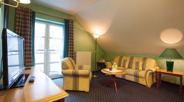 Wohnzimmer mit grüner Wandfarbe im Park Resort mit gestreifter Couch mit passendem Sessel 