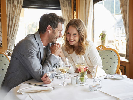 Lachendes Paar hält Händchen und sitzt an einem Tisch in einem Restaurant 