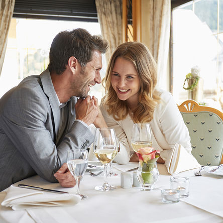 Lachendes Paar hält Händchen und sitzt an einem Tisch in einem Restaurant 