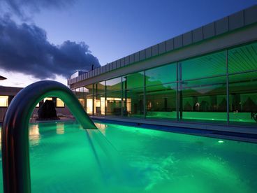 Außenpool mit Wasserstrahl in der Dämmerung
