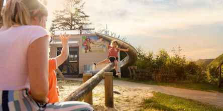 Ein Kind rutscht auf einer Rutsche, während Erwachsene zuschauen