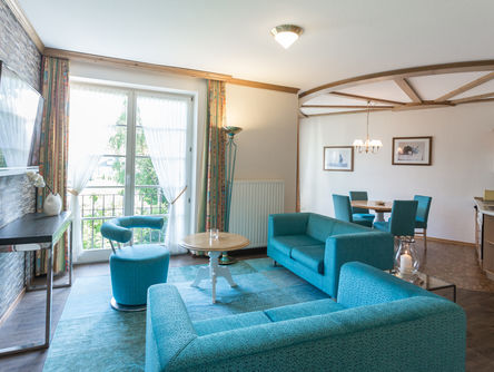 Wohnbereich mit Zugang zum Balkon, eingerichtet mit einer blauen Couch und passenden Esszimmerstühlen 