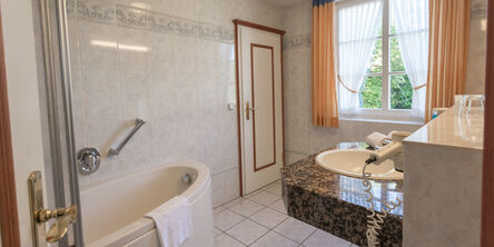 Badezimmer mit Badewanne und einem Föhn am Waschbecken 