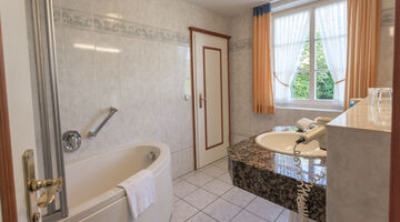 Badezimmer mit Badewanne und einem Föhn am Waschbecken 