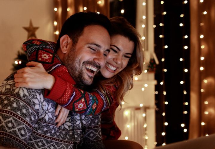 Pärchen in Weihnachtspullis ist am lachen