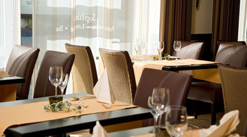 [Translate to english:] Tische und Stühle in erdfarben geben dem Restaurant "Fräulein Sophies" eine ruhige Atmosphäre.