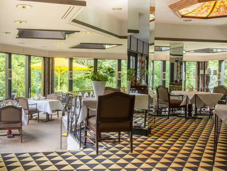 Einblick in das lichtdurchflutete Restaurant mit deckenhohen Fenstern mit Blick ins Grüne 