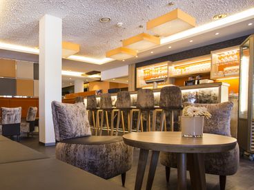 Samtsessel an einem runden Tisch in der Bar mit Samtbarhockern am Tresen 