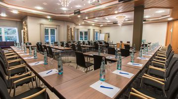 Seminarraum mit zahlreichen Plätzen vorbereitet mit Getränken und Schreibutensilien 