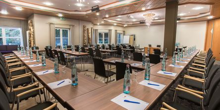 Seminarraum mit zahlreichen Plätzen vorbereitet mit Getränken und Schreibutensilien 